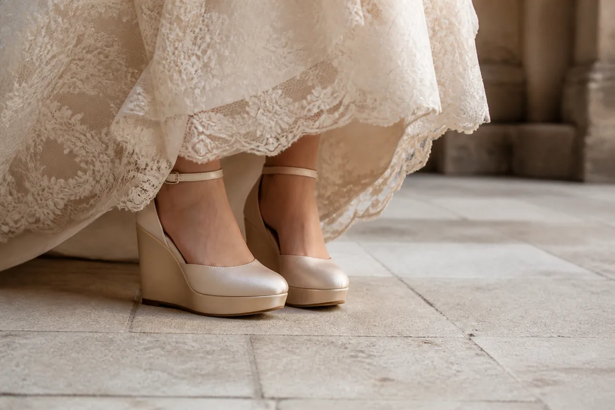 Chaussures compensées champagne assorties à l&rsquo;ourlet d&rsquo;une robe de mariée en dentelle