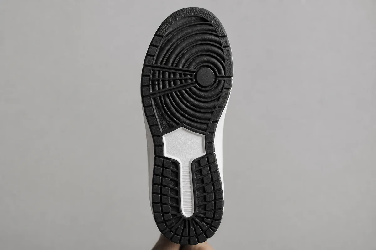 Semelle extérieure d&rsquo;une chaussure de training présentée de face, relief de gomme apparent