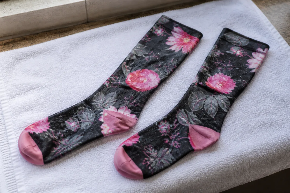 Chaussettes de compression étendues à plat sur une serviette éponge près d’une fenêtre